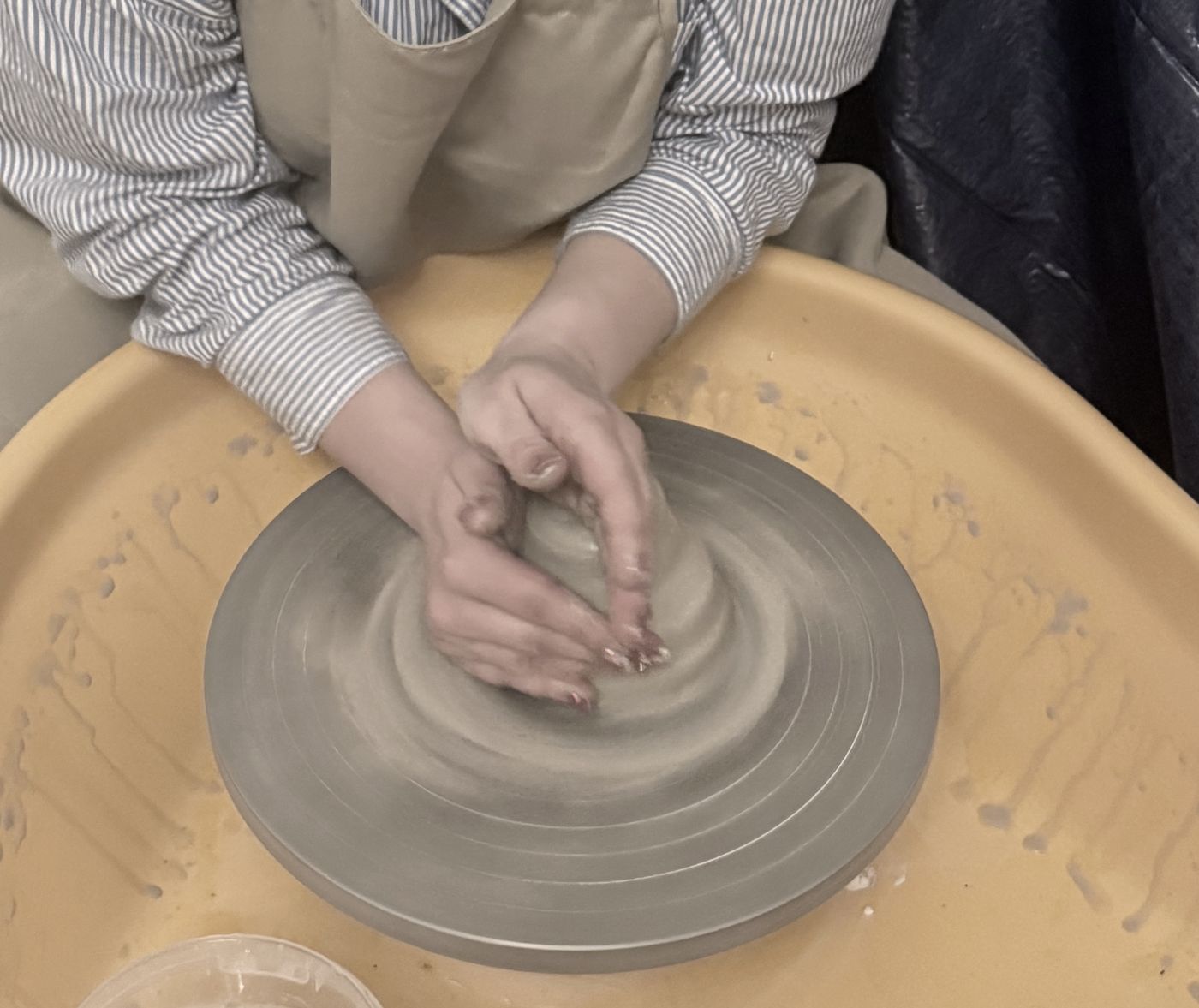 Hands centring clay on a potter's wheel